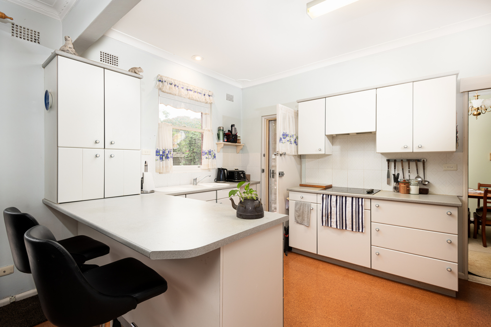 St Ives, Sydney, Australia - Nov 12 2020: Small 70's retro style kitchen in suburban home residence with laminex cabinets and linoleum flooring, benches, cook top and sink